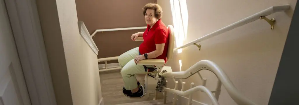 Elderly woman on a stairlift after learning and implementing tips for aging in place