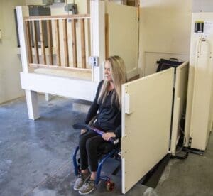 Lady in a wheelchair about to use a vertical platform lift