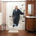 elderly man in a robe using a low barrier to exit a shower